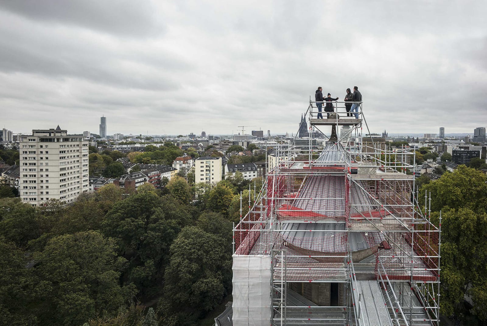 Vier Menschen auf dem Baugerüst einer Kirche ganz oben